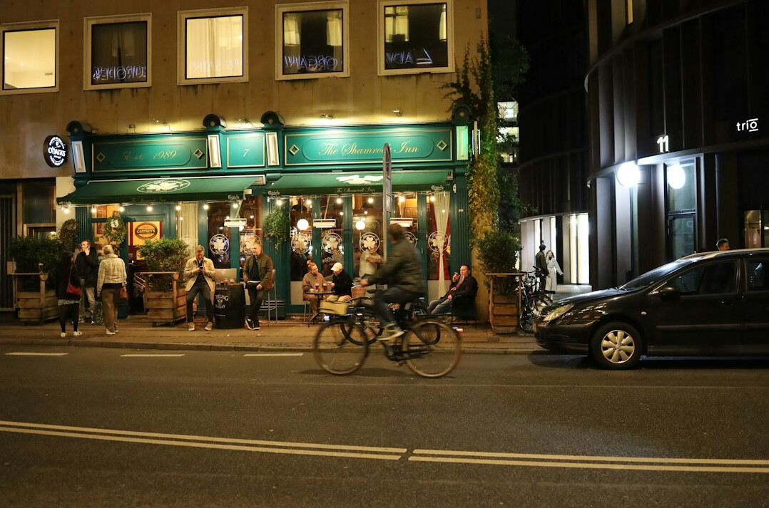 People queuing at a night bus stop under streetlights in Denmark